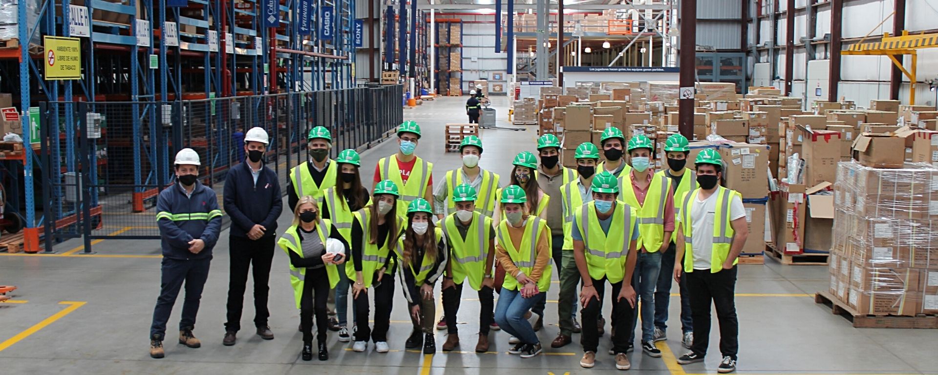 Alumnos de Negocios Internacionales posando dentro de la planta de Costa Oriental, usando cascos y tapabocas