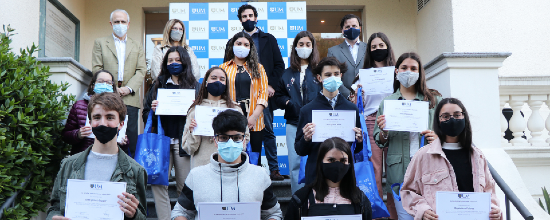 Estudiantes ganadores muestran sus diplomas en las escaleras del jardín de la UM.