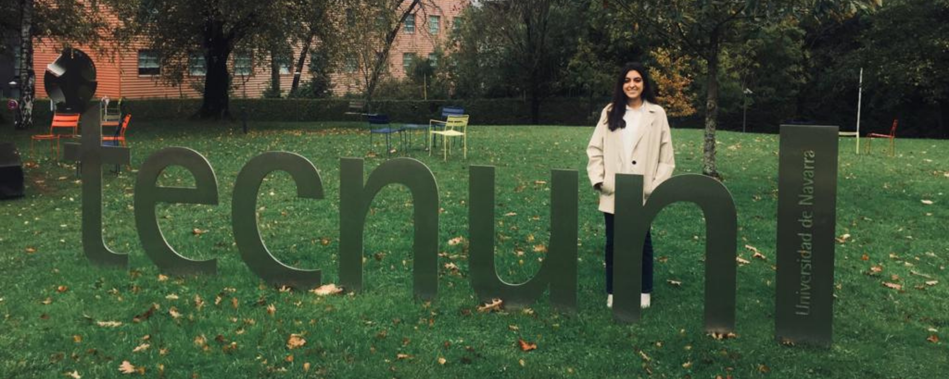 La graduada de la UM Florencia Kalemkerian en el jardín de Tecnun, junto a un cartel con ese nombre.