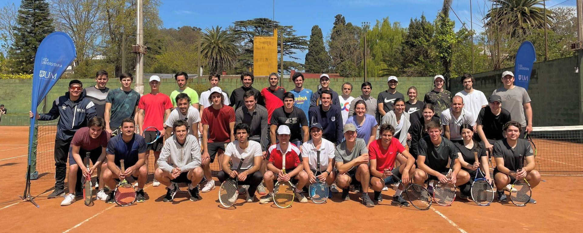 Torneo de tenis UM 2022, posan frente a cancha 42 participantes con raquetas al sol